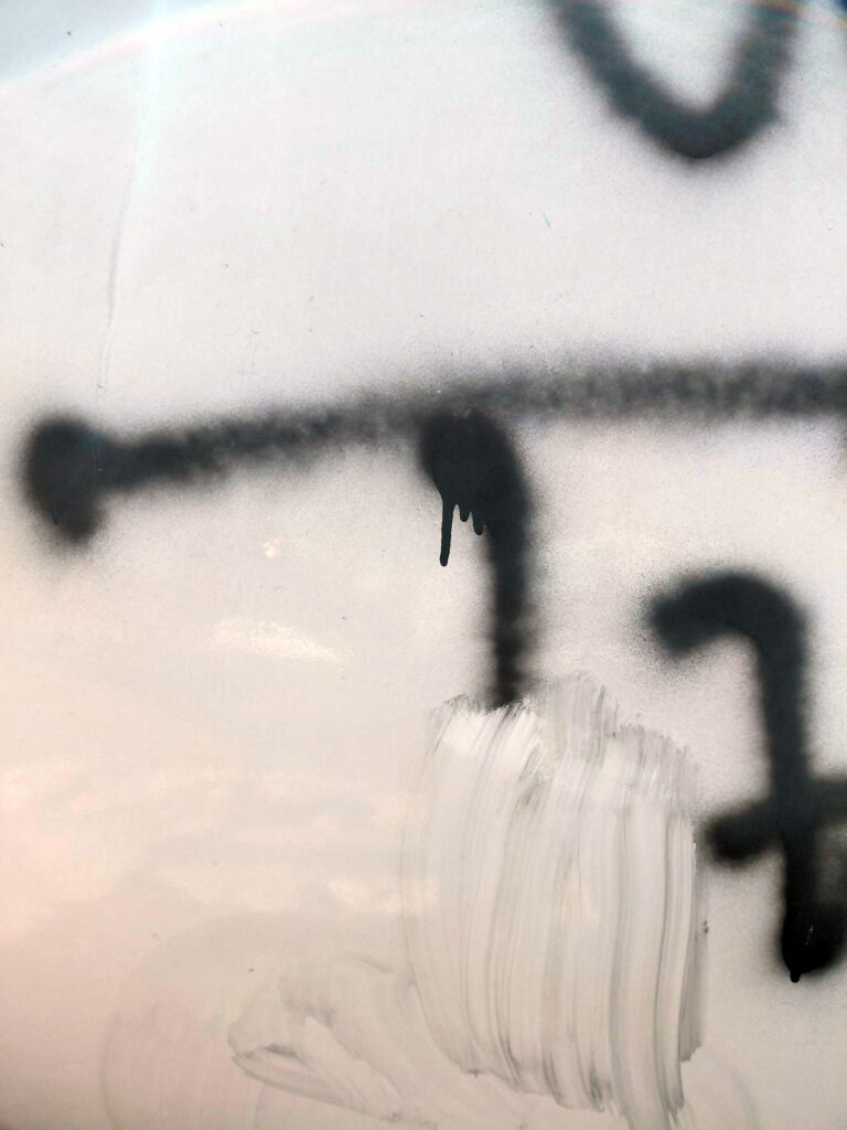 Musta spraymaali vaaleanpunaisen taideteoksen pinnalla.